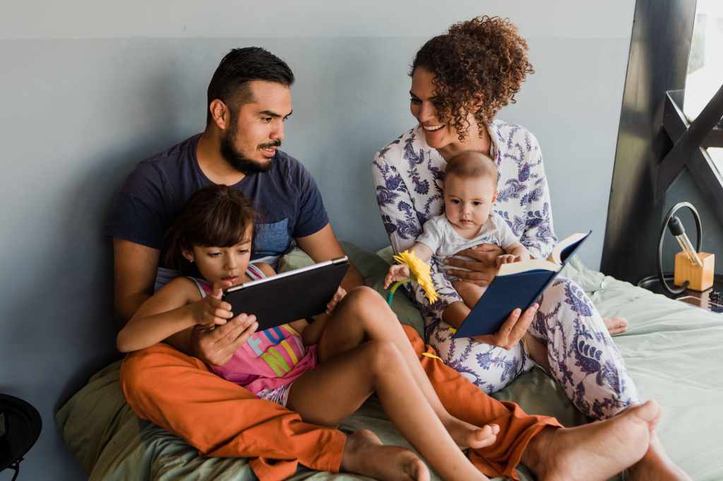 Familie mit zwei kleinen Kindern benutzt ihren Laptop im Bett